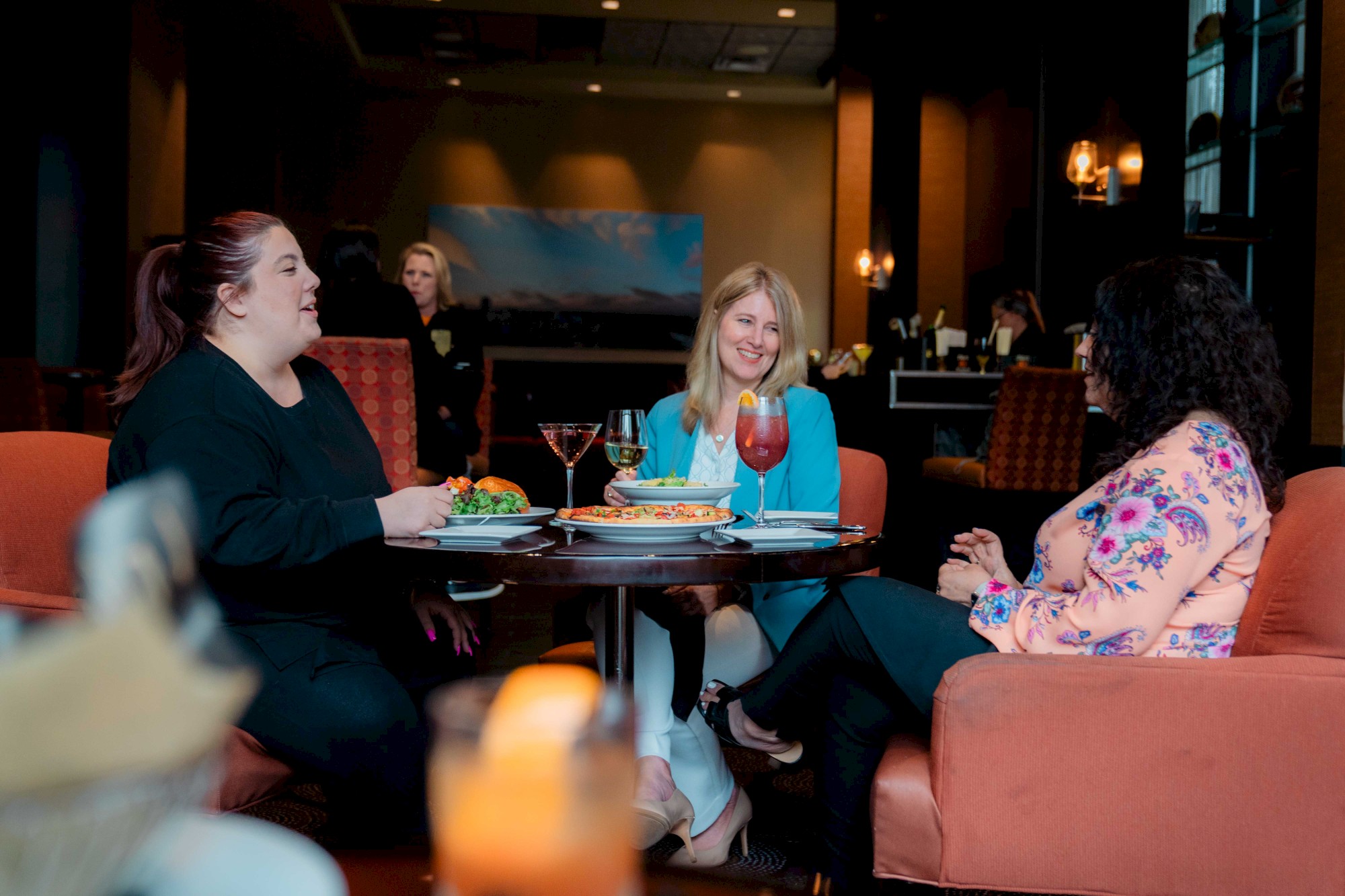 Photo of three people having a meal in an elegant restaurant while laughing