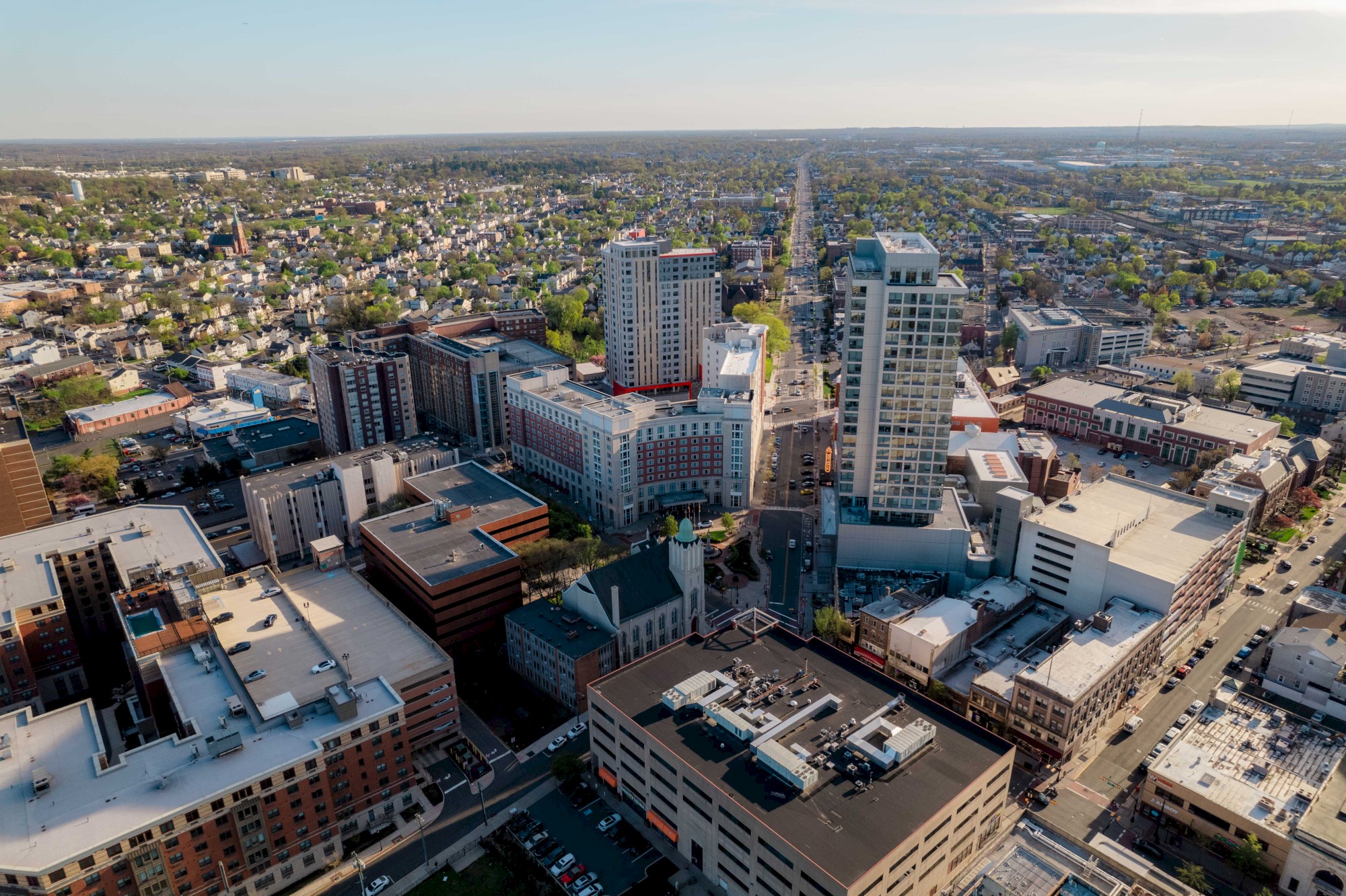 Aerial view of a cityscape featuring tall buildings, residential areas, and roads stretching into the distance.