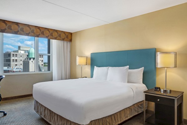 Photo of luxury modern hotel room with king size bed and big window with curtain