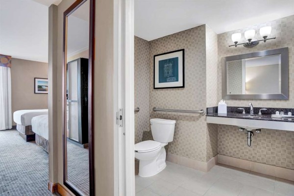 Photo of luxury modern hotel room with double beds, mirror on the corridor and bathroom with mirror and marble counter