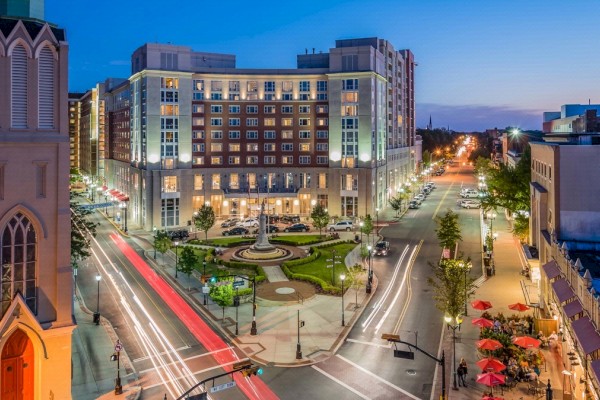 Night Photo of The Heldrich Façade with green grass and statue plaza and traffic incoming from both sides