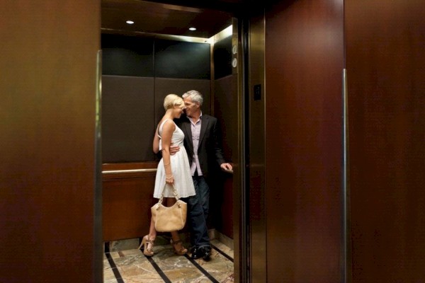 Photo of happy couple on the elevator with the doors open while they are hugging