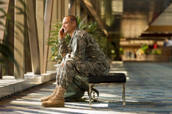 photo of person with military uniform seating on a chair in a lounge area having a phone call while smiling