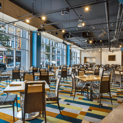 photo of multiwindow inside restaurant with multiple chairs and tables in a colorful floor