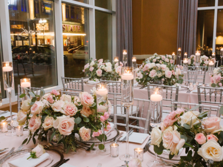 Photo of event table set up with multiple flower centerpieces and elegant chairs