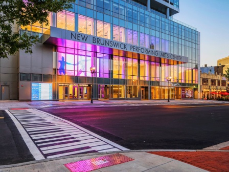 Photo of crosswalk path with theater in front, in an evening set