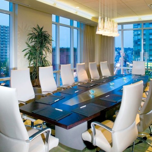 Photo of meeting room in u set up with white wheeled chairs, multiple windows and an elegant black table