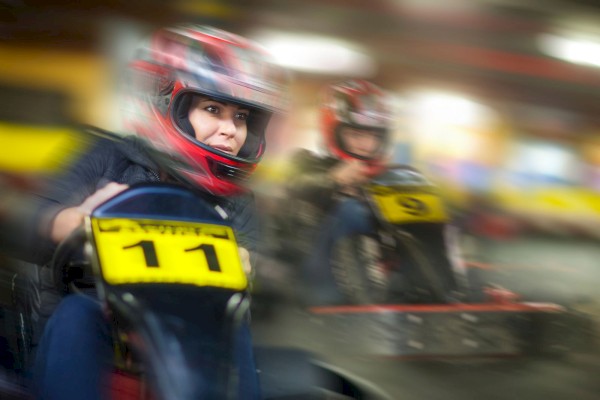 Photo of two people racing on go karts with helmets on