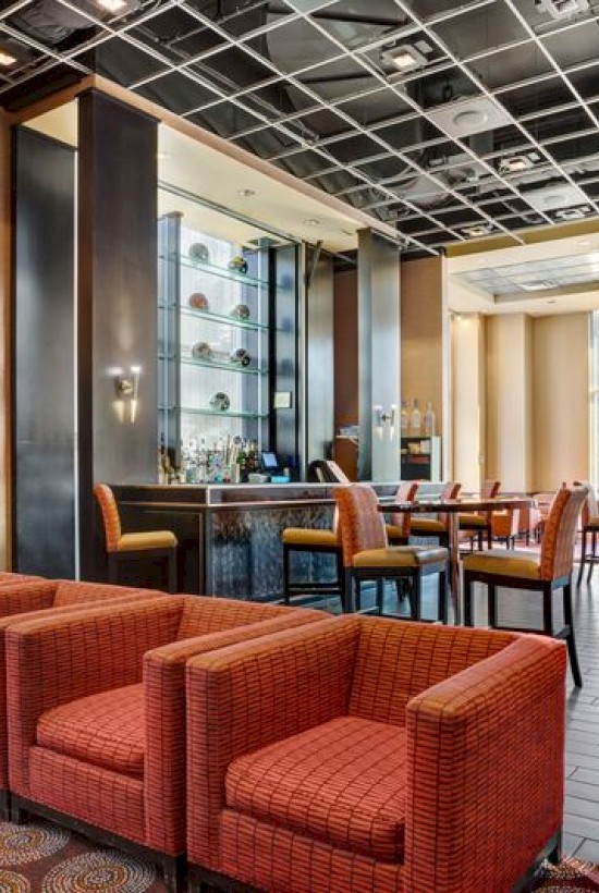 photo of lounge hotel area with multiple red couches, orange chairs and tables, with natural light