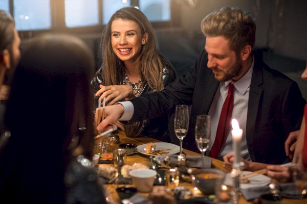 photo of four people in a business dinner talking and a table full of different dishes and drinks