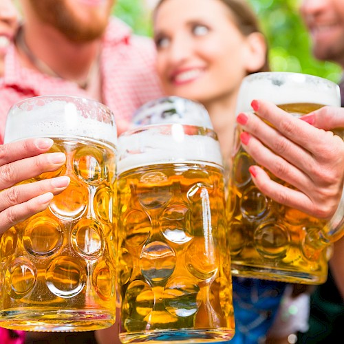 People are clinking large beer mugs, celebrating in a festive atmosphere.