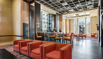 Photo of lounge hotel with multiple red sofa chairs and orange high chairs