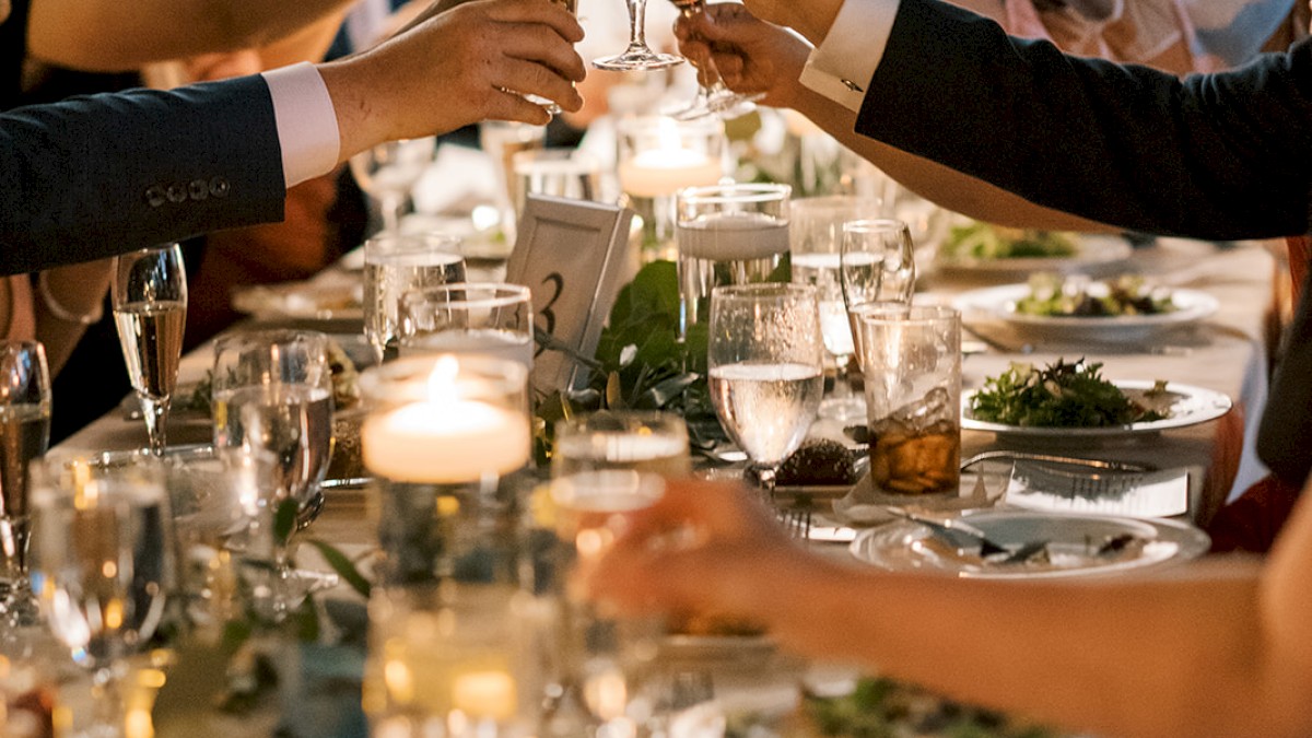 Photo of meeting food event with multiple people sitting in a long table chatting dressed in business casual