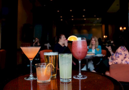 Four drinks on a table in a dimly lit lounge, with people chatting in the background.